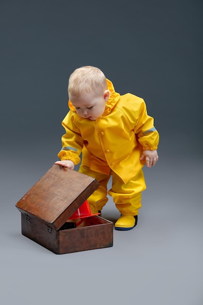Uma criança em traje de bombeiro espreita em caixa de madeira