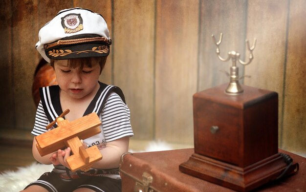 Uma criança em um interior retrô e um telefone antigo se senta no chão. uma criança pequena, um viajante em decorações vintage. viajante infantil está ligando por telefone.