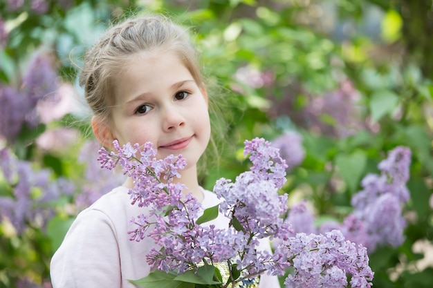 Uma criança em um lilás Linda menina pré-escolar com um buquê de flores da primavera