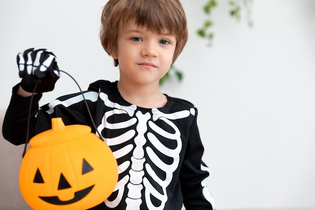 uma criança em uma fantasia de halloween fica com lugar decorado de abóbora