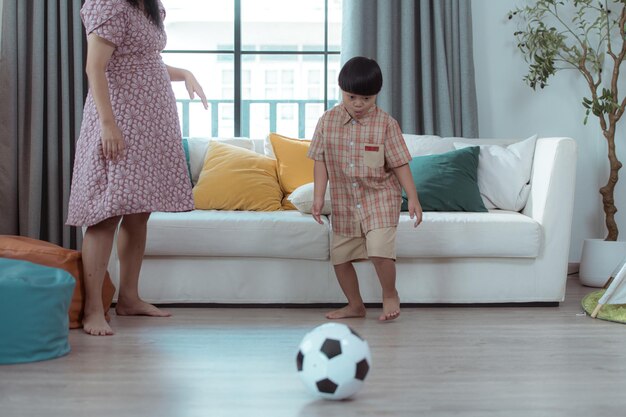 Uma criança especial com sua mãe jogando futebol juntos na sala de estar da casa