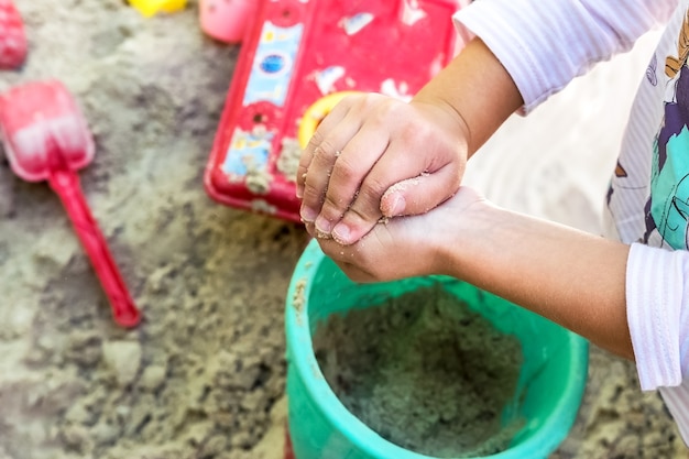 Uma criança está brincando na caixa de areia. Ele faz diferentes formas de areia