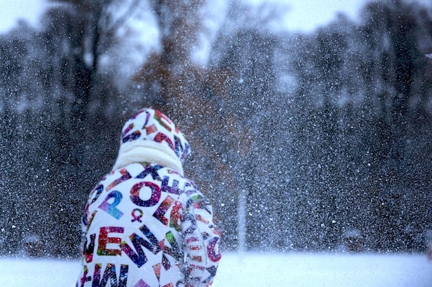 Uma criança está se movendo na rua durante uma queda de neve
