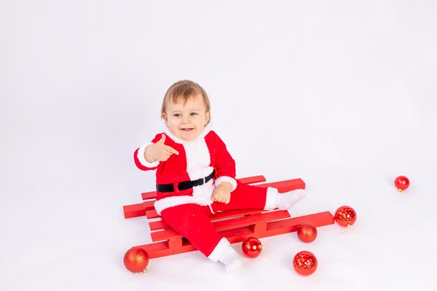 Uma criança fantasiada de Papai Noel com bolas vermelhas de Natal