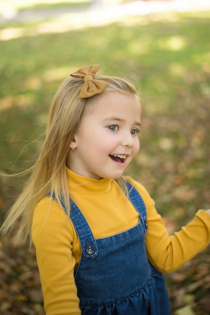 Uma criança feliz em um parque de outono contra o fundo de folhas amarelas borradas