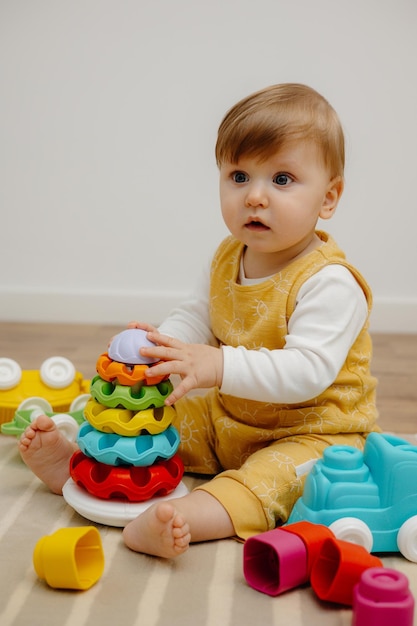 Uma criança fofa está brincando com uma pirâmide colorida de brinquedos de arco-íris Brinquedos para crianças pequenas