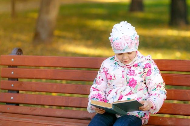 Uma criança fofa está lendo um livro no parque.