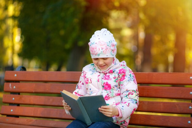 Uma criança fofa está lendo um livro no parque.