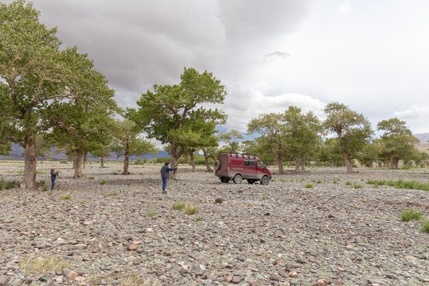 Uma criança fotografa um pai que fotografa um carro no fundo das montanhas da Mongólia