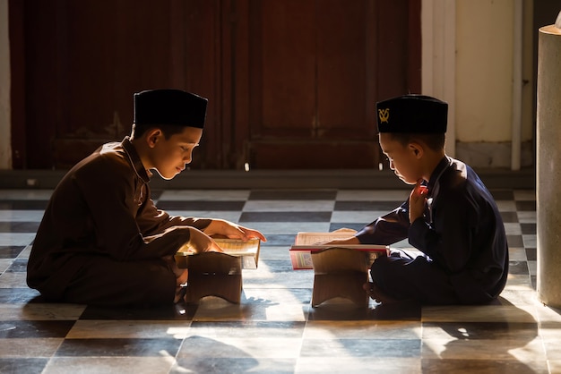 Uma criança islâmica ora para estudar com sua irmã e seu irmão em uma mesquita em Songkhla, Tailândia.