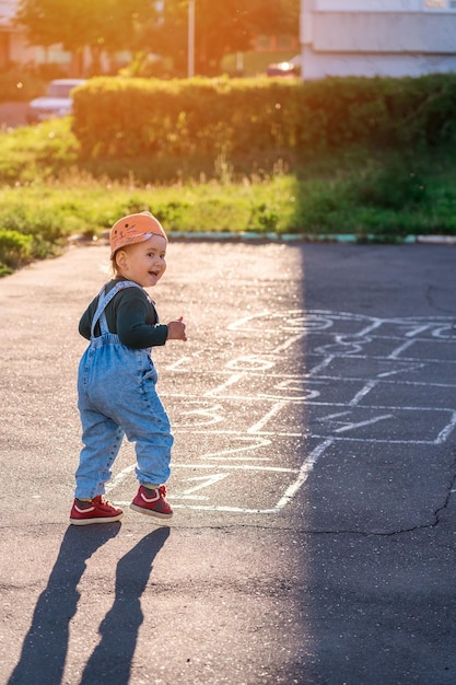 Foto uma criança joga amarelinha no playground durante o pôr do sol