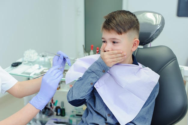 Uma criança menino com um dentista em um consultório odontológico