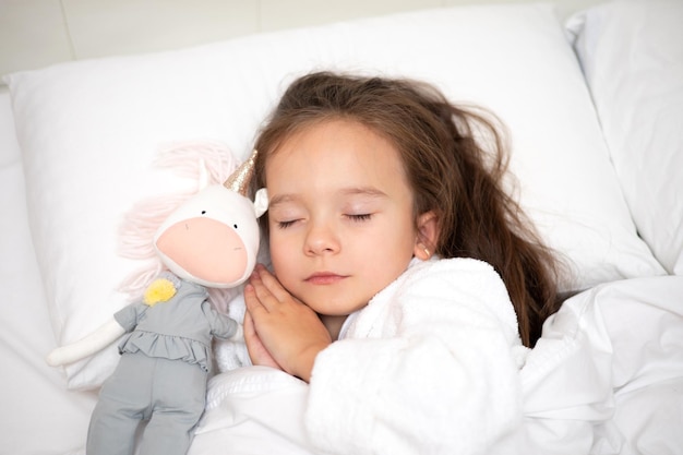 Uma criança na cama dorme com um brinquedo Cores claras Modo de estilo de vida do dia Sono e descanso saudáveis