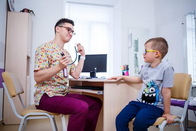 Uma criança no consultório médico, o médico ouve os pulmões do menino. Exame médico da criança