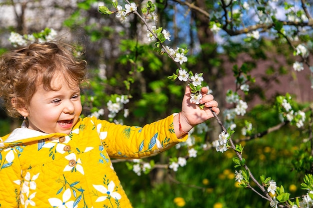 Uma criança no jardim cheira uma árvore de primavera em flor Foco seletivo