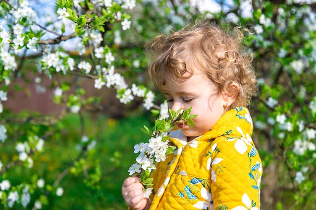 Uma criança no jardim cheira uma árvore de primavera em flor Foco seletivo