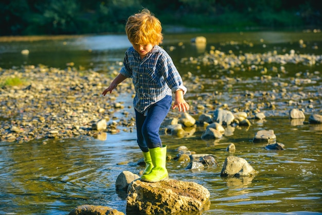 Uma criança no lago ou rio a criança caminha pelo rio anda no parque em um dia ensolarado de primavera