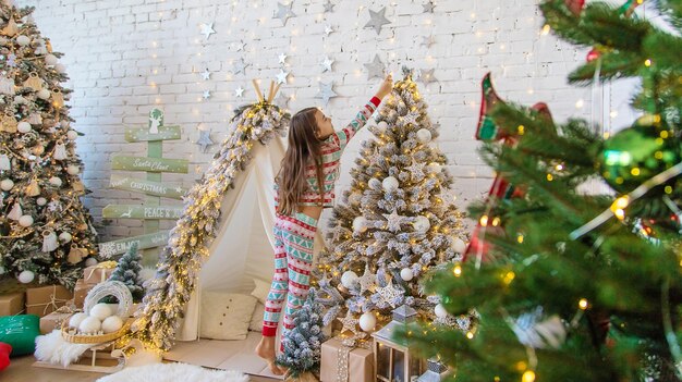 Uma criança pendura uma estrela em uma árvore de Natal Foco seletivo