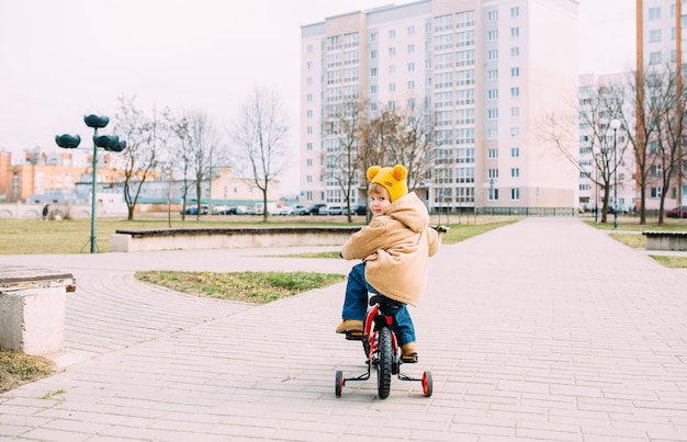 uma criança pequena aprende a andar de bicicleta pela primeira vez na cidade na primavera