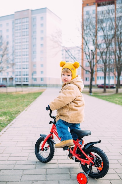 uma criança pequena aprende a andar de bicicleta pela primeira vez na cidade na primavera