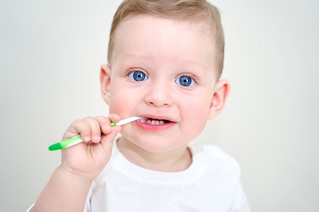 Uma criança pequena com olhos azuis segura uma escova de dentes nas mãos