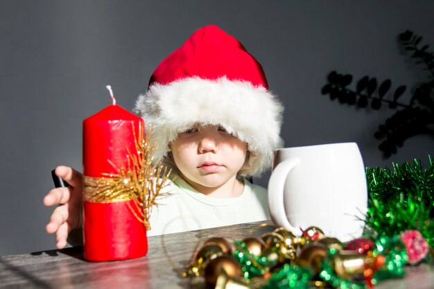 Uma criança pequena com um chapéu de Papai Noel com presentes na mesa de Ano Novo