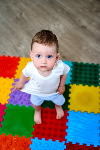 Uma criança pequena em um tapete ortopédico com os pés descalços.