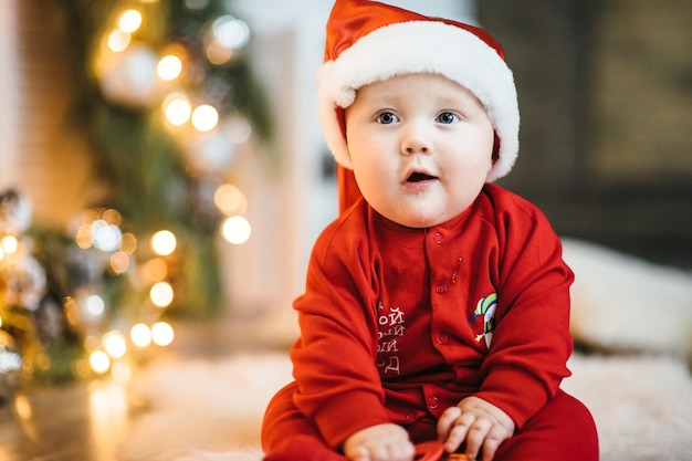 Uma criança pequena em um terno vermelho senta-se no chão