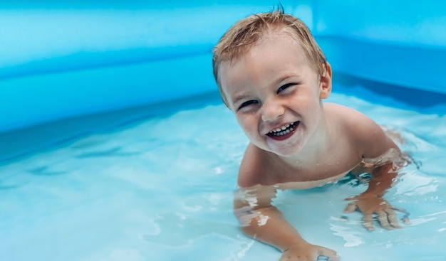 Uma criança pequena em uma piscina infantil inflável em um clima ensolarado de verão. conceito de verão e férias.