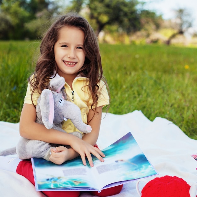 Uma criança pequena está lendo um livro e sorrindo. Quadrado. O conceito