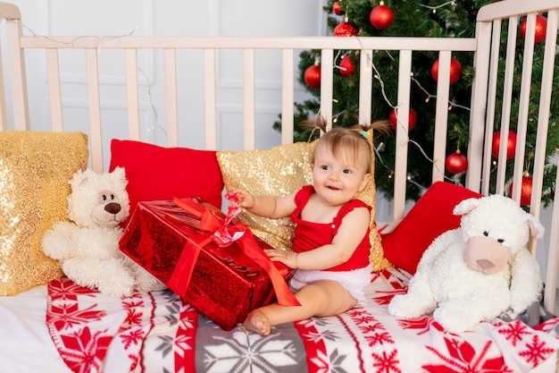 Uma criança pequena na cama ao lado de uma árvore de natal