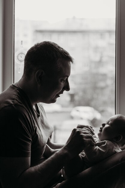 Uma criança pequena, um recém-nascido nos braços do Papa, um retrato de uma criança, infância e família, mãos de bebê