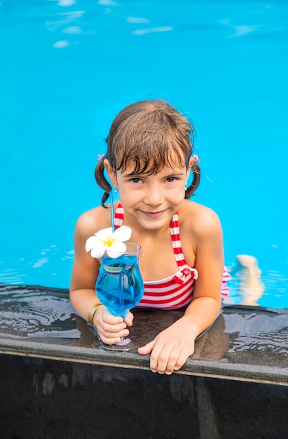 Uma criança perto da piscina bebe um coquetel.