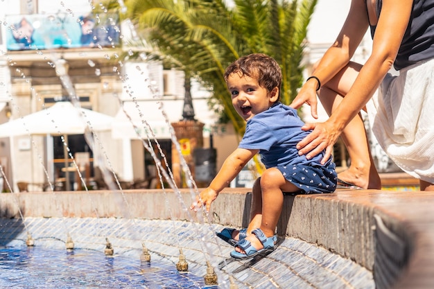 Uma criança se refrescando na fonte de água na Plaza de Espana em Vejer de la Frontera Cádiz