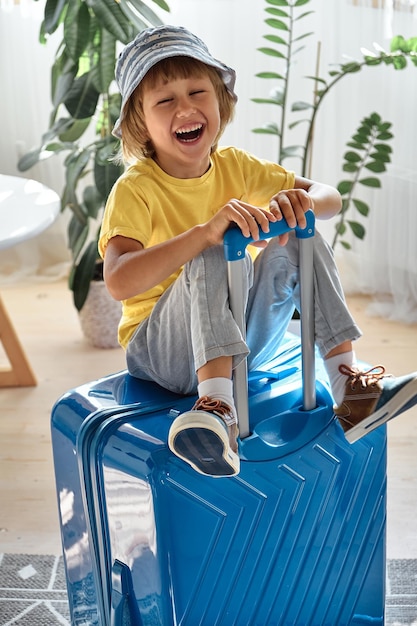 Foto uma criança sentada em uma mala se diverte e ri esperando uma viagem de férias