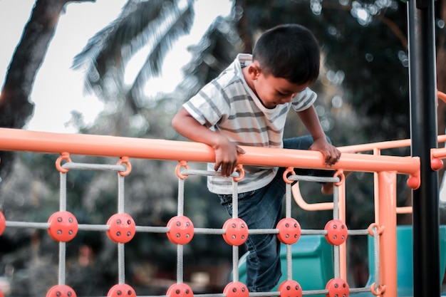 Uma criança sobe uma grade alpina em um parque em um playground em um dia quente de verão playground infantil em um parque público entretenimento e recreação para crianças