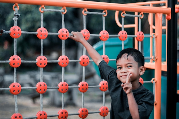 Uma criança sobe uma grade alpina em um parque em um playground em um dia quente de verão playground infantil em um parque público entretenimento e recreação para crianças