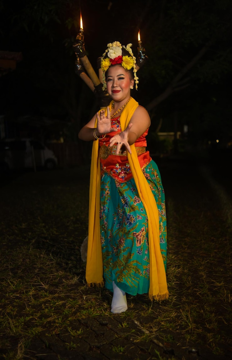 Foto uma dançarina tradicional javanesa dança com flores coloridas no punho enquanto está no palco à noite