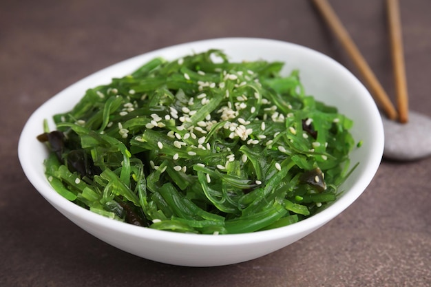 Uma deliciosa salada de algas em uma tigela servida em uma mesa marrom de perto