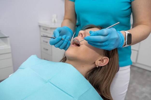 Uma dentista e seu assistente examinam os dentes de uma mulher que veio à recepção