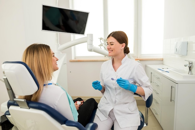 Uma dentista feminina explica a um paciente gesticulando com as mãos O conceito de tratamento odontológico odontológico