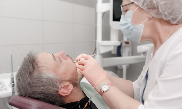 Uma dentista trata os dentes de um paciente do sexo masculino em um consultório moderno de uma clínica odontológica