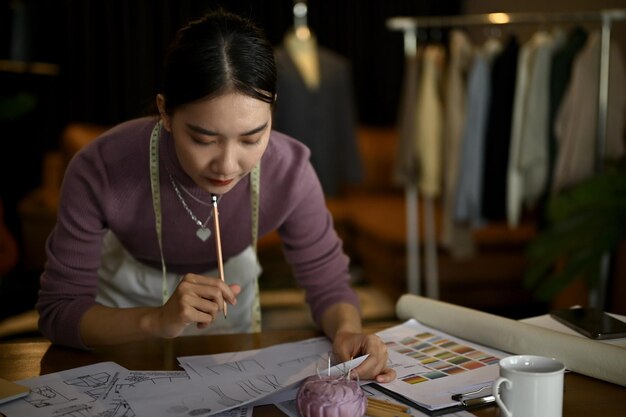 Uma designer de moda feminina se concentra em projetar e esboçar novos modelos de fantasias em seu estúdio