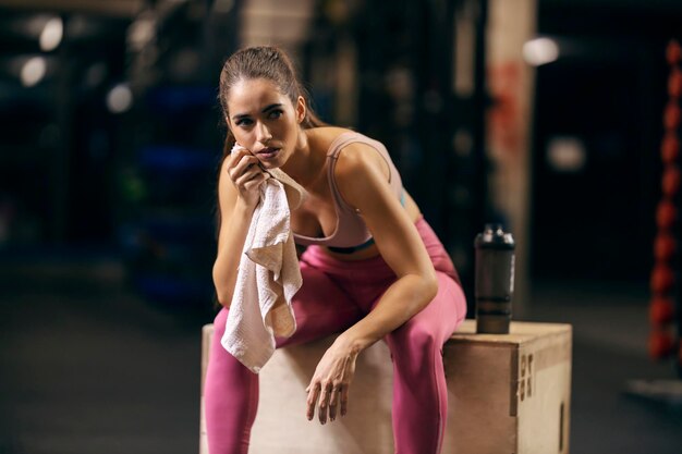 Foto uma desportista cansada está a limpar o suor com uma toalha enquanto faz uma pausa num ginásio