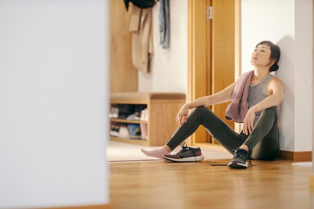 Uma desportista japonesa cansada está fazendo uma pausa depois de exercícios em casa