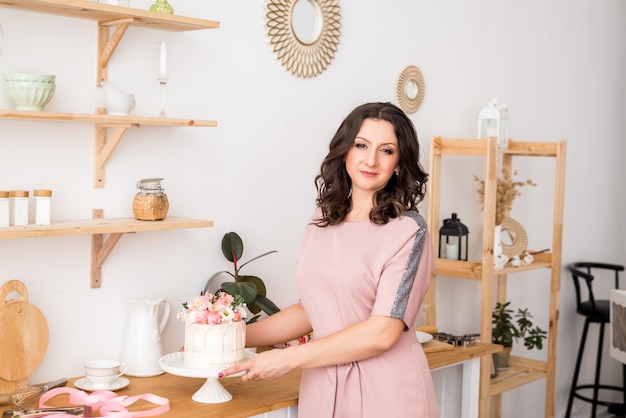 Uma dona de casa uma chef de pastelaria mulher na cozinha preparou um bolo e uma sobremesa doce