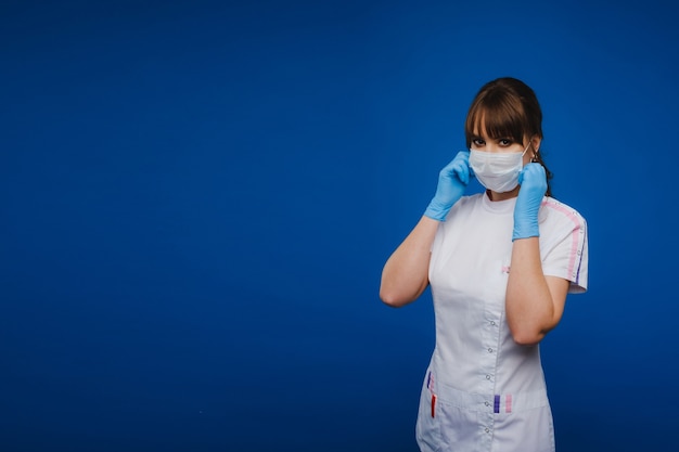 Uma doutora está com uma máscara médica, isolada em um fundo azul.
