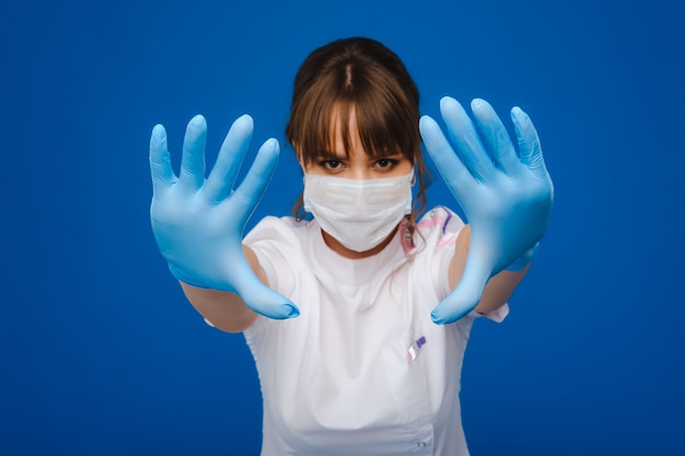 Uma doutora está com uma máscara médica, isolada em um fundo azul.