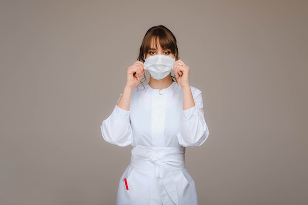 Uma doutora está com uma máscara médica, isolada em um fundo cinza.