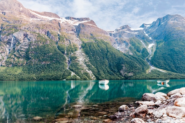 Uma embarcação náutica vazia no lago idílico perto da montanha da rocha